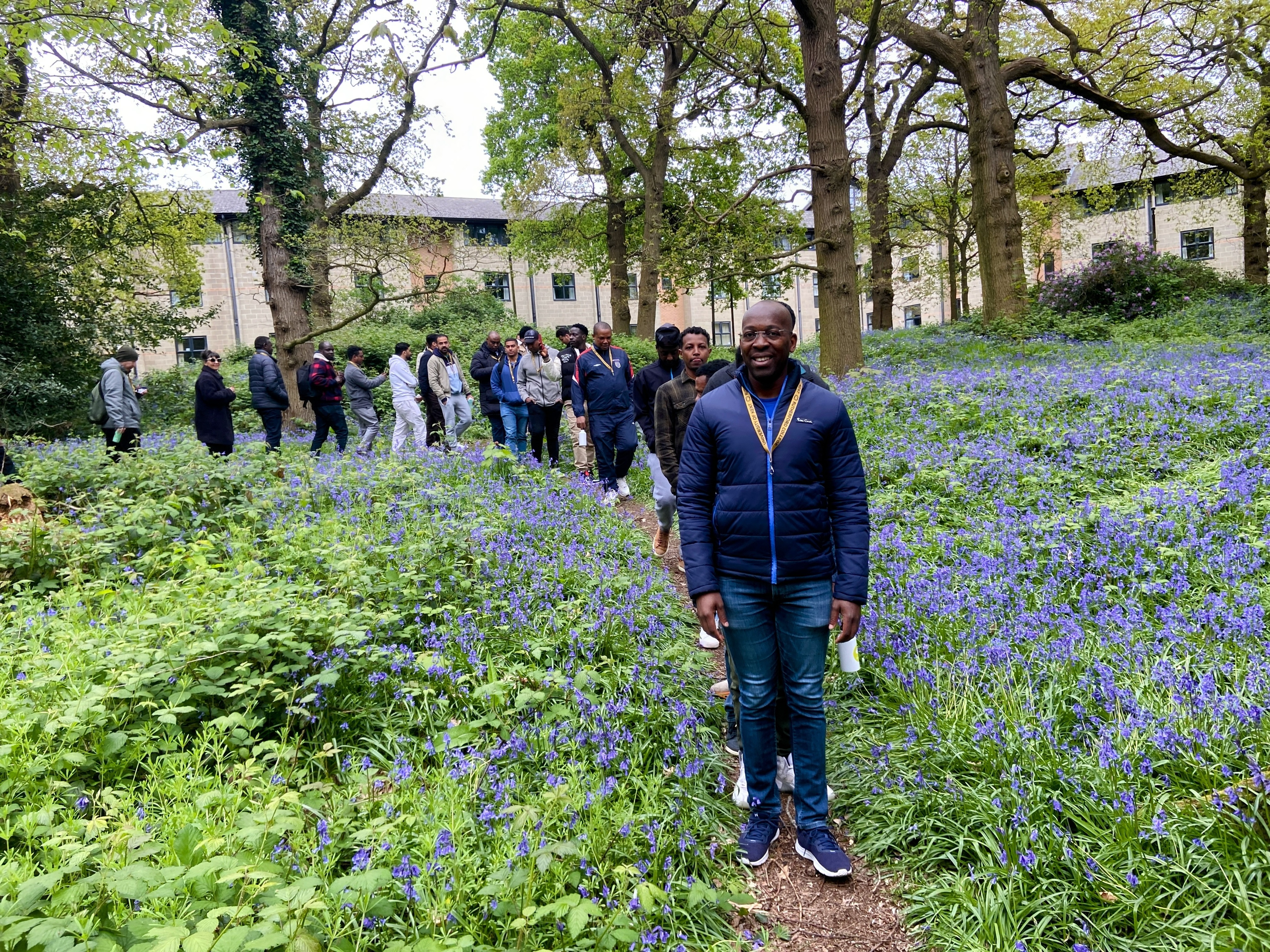 Photo of group of 30 men walking through the bluebell woods on University of Kent campus