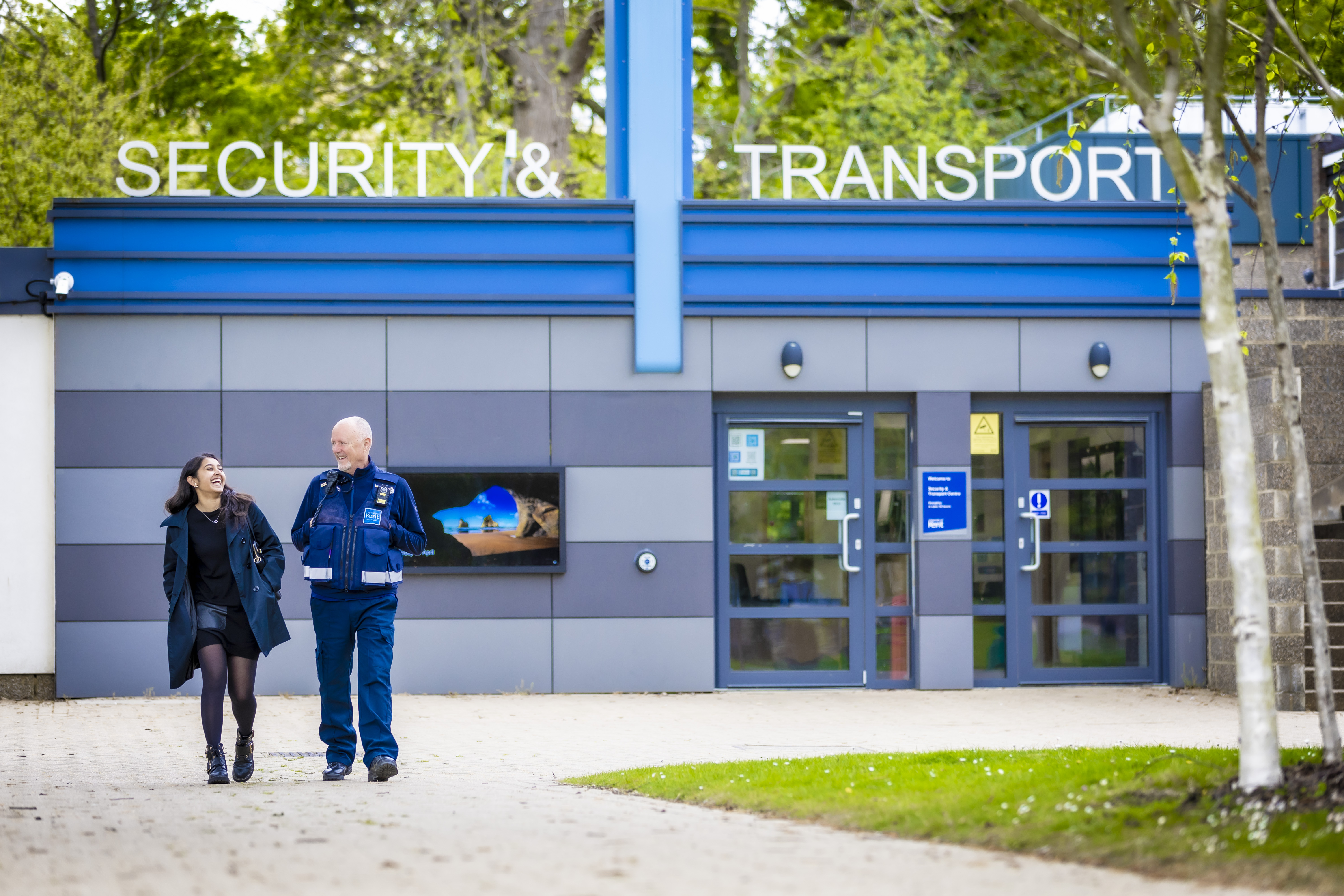 student and security walking in front of security office on campus