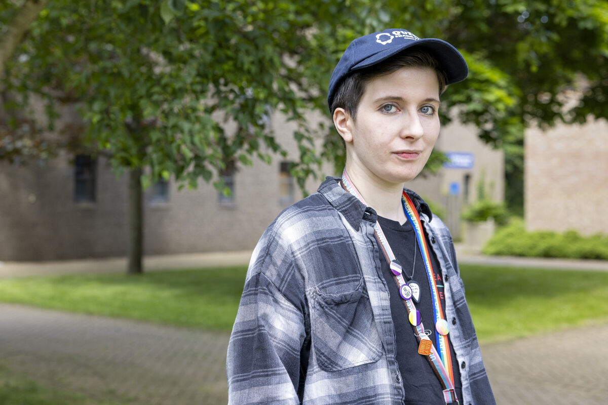 PhD student Sid wearing rainbow lanyard with LGBTQ+ inclusive badges