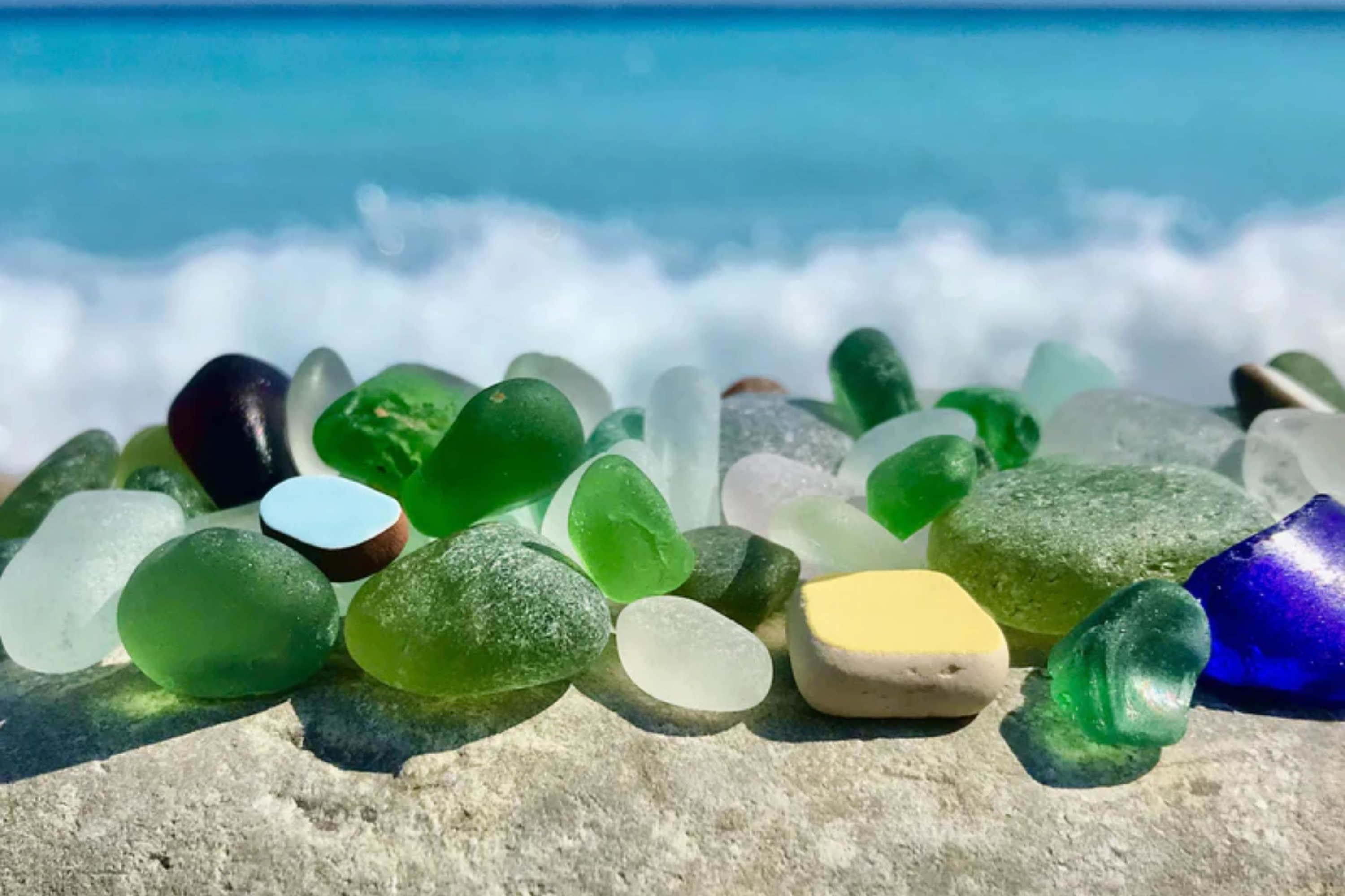 Seaglass on beach with sea in background.