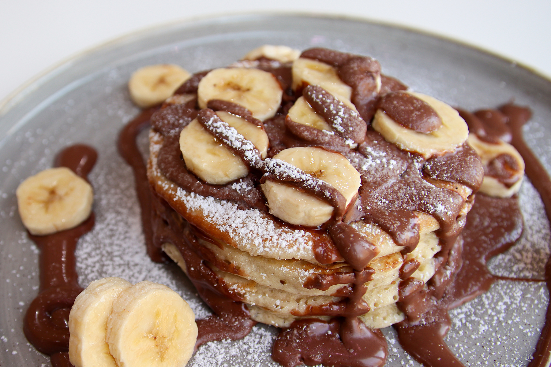 A stack of American style pancakes topped with Nutella and banana