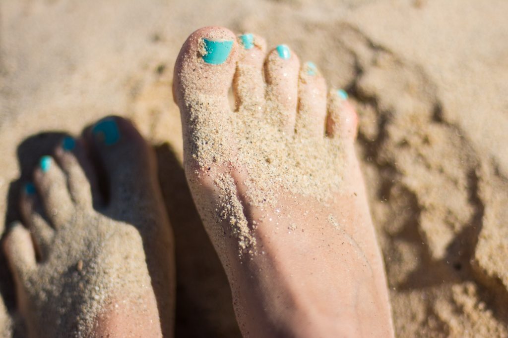 a photo of feet playing in the sand on a sunny day