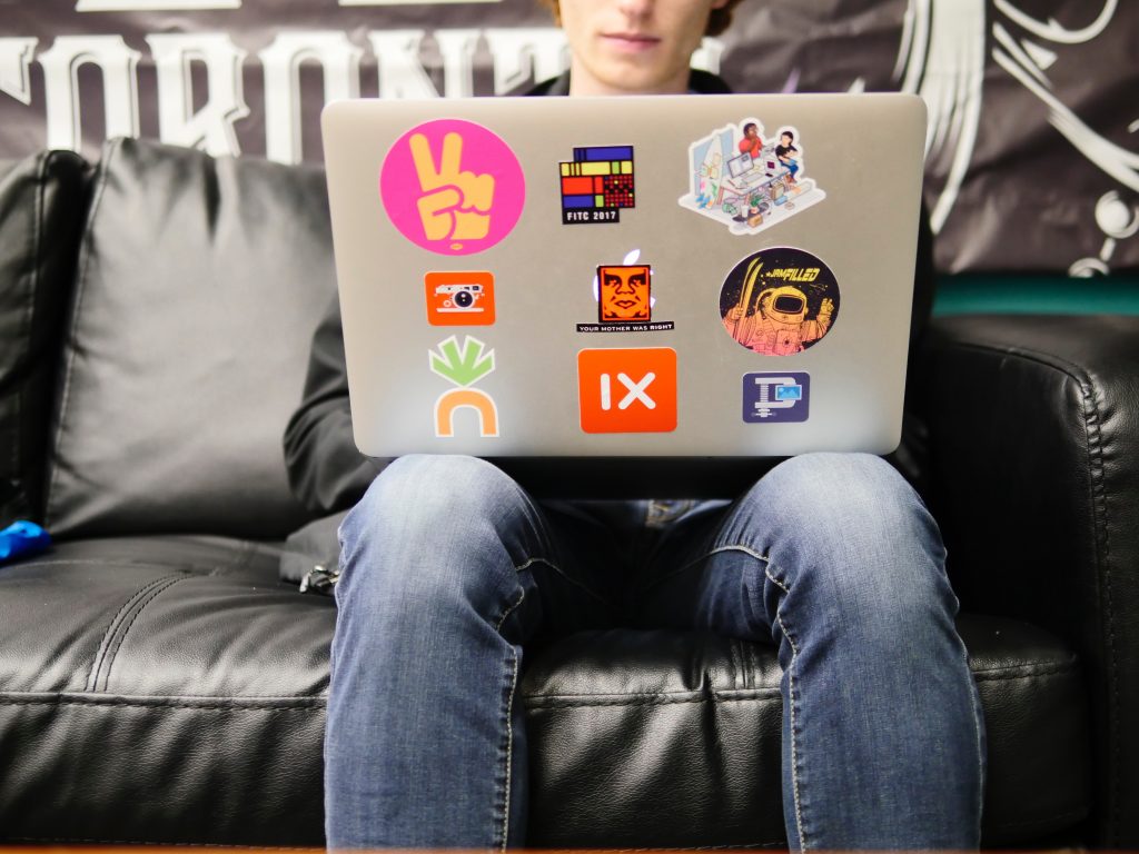 View of an open laptop with sticker on it sitting on a persons lap